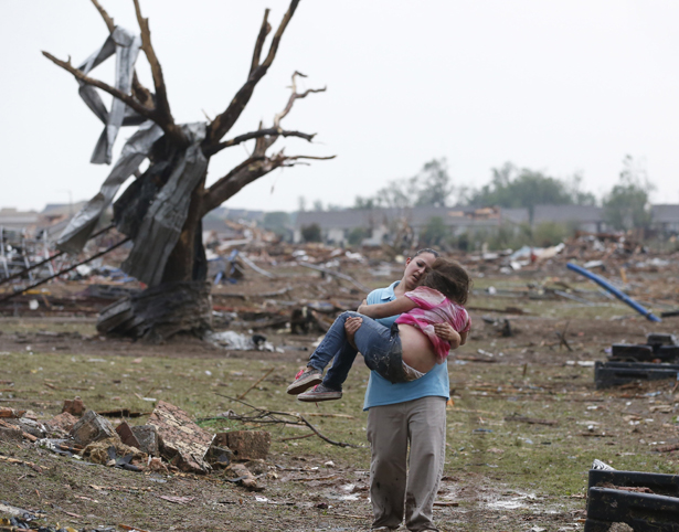 A woman carries her child after the tornado in Moore, OK