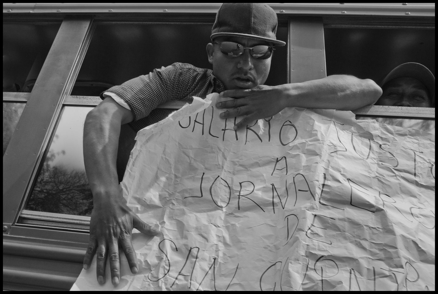 A striking farm worker on a bus from the San Quintin Valley holds a sign demanding: A Fair Wage for Farm Workers in San Quintin.