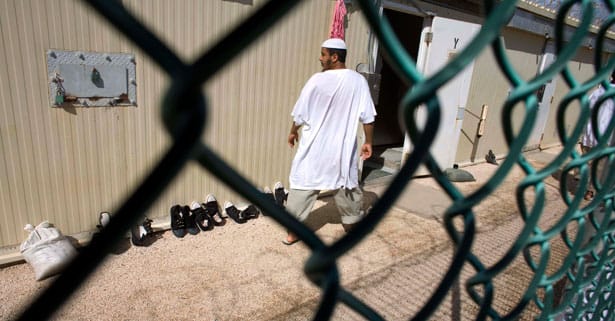 pemA-Guantanamo-detainee-walks-past-a-cell-block-at-Camp-4-detention-facility-Nov.-18-2008.-AP-PhotoBrennan-Linsleyemp