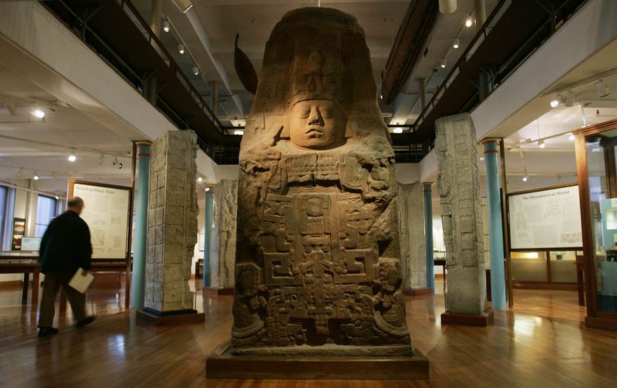 A man walks past a giant plaster cast on display with other artifacts at the Peabody Museum.
