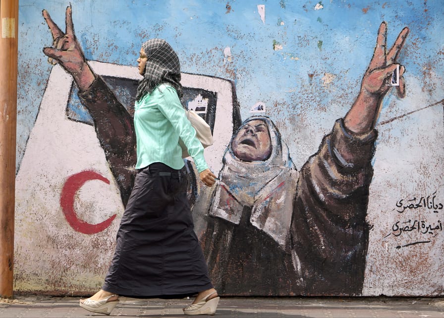 Palestinian-woman-walks-by-mural