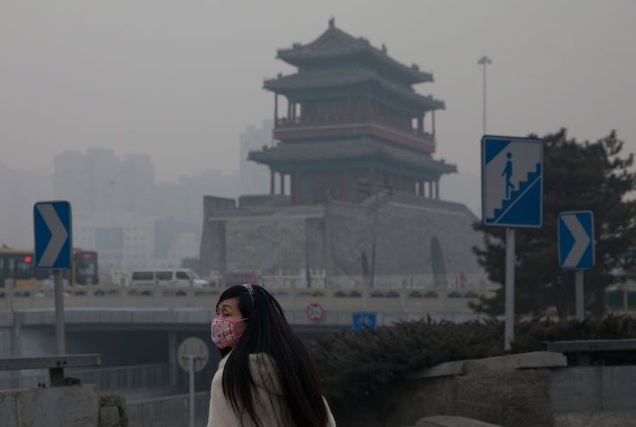A-woman-wears-a-mask-as-she-walks-under-smog-in-Beijing-China.-AP-PhotoAlexander-F.-Yuan