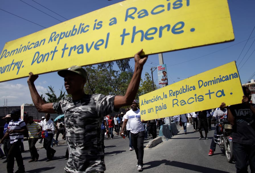 Protesters holds signs while marching on a street in Port-au-Prince