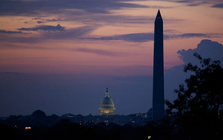 The Washington Monument and US Capitol silhouetted at dawn in Washington, DC.