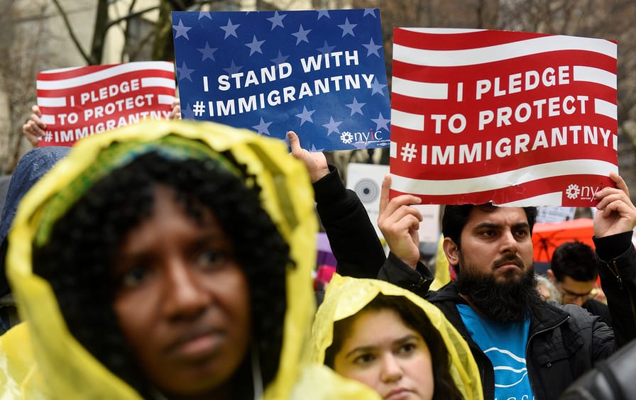 People hold up signs at an immigration rally