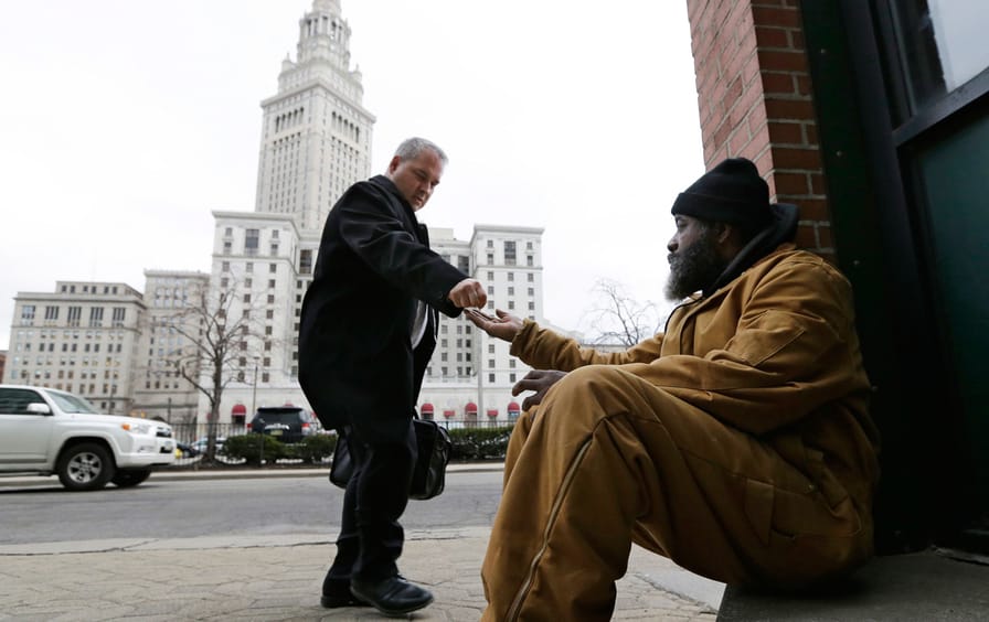 Kenny Chapman, 53, receives coins from a man