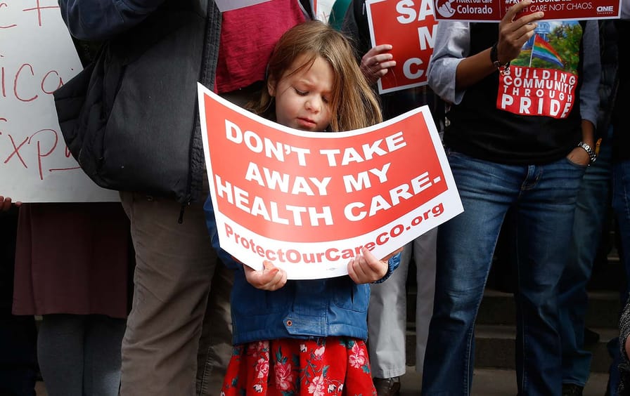 A girl stands holding a sign alongside supporters of the Affordable Care Act at a rally in Denver on Tuesday, January 31, 2017.