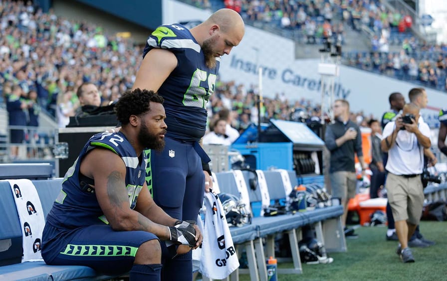 Michael Bennett sits during the national anthem.