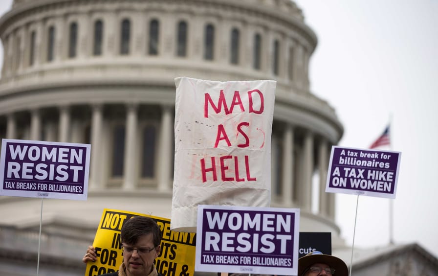 Demonstrators hold up protest signs in front of the United States Capitol