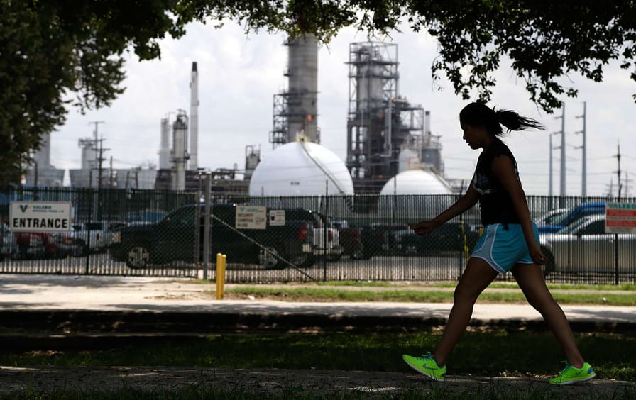 Girl walks past Houston oil refinery