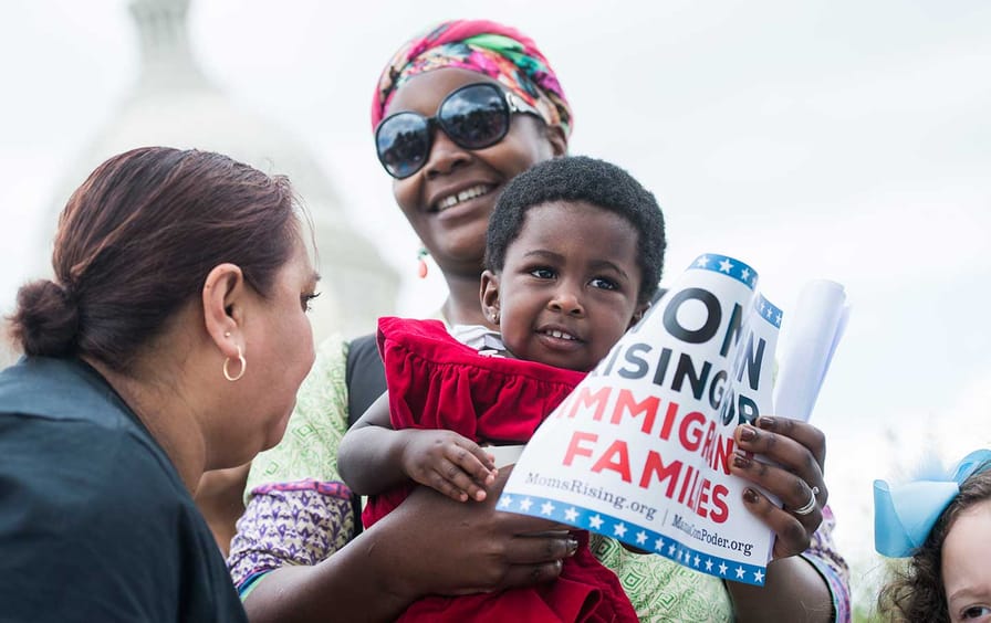 Hawa Tembe, 18 months, whose mother, Didi, in sunglasses, is from Mozambique, joins mothers and caregivers during news conference at the House Triangle to call on lawmakers to protect 