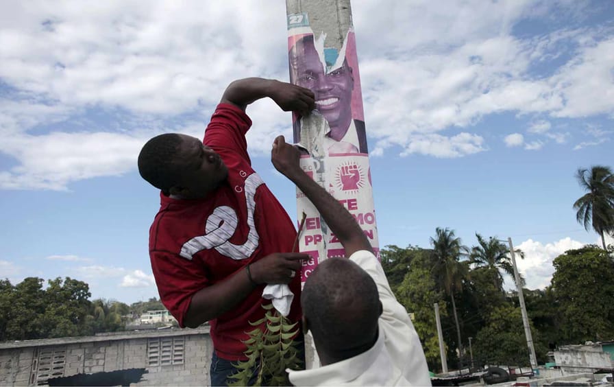 Protesters rip an electoral poster of president Jovenel Moïse