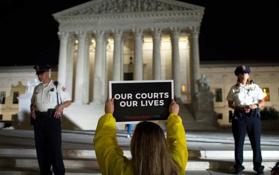 A demonstrator protests in front of the Supreme Court as President Donald Trump announces Judge Brett Kavanaugh as his Supreme Court nominee.