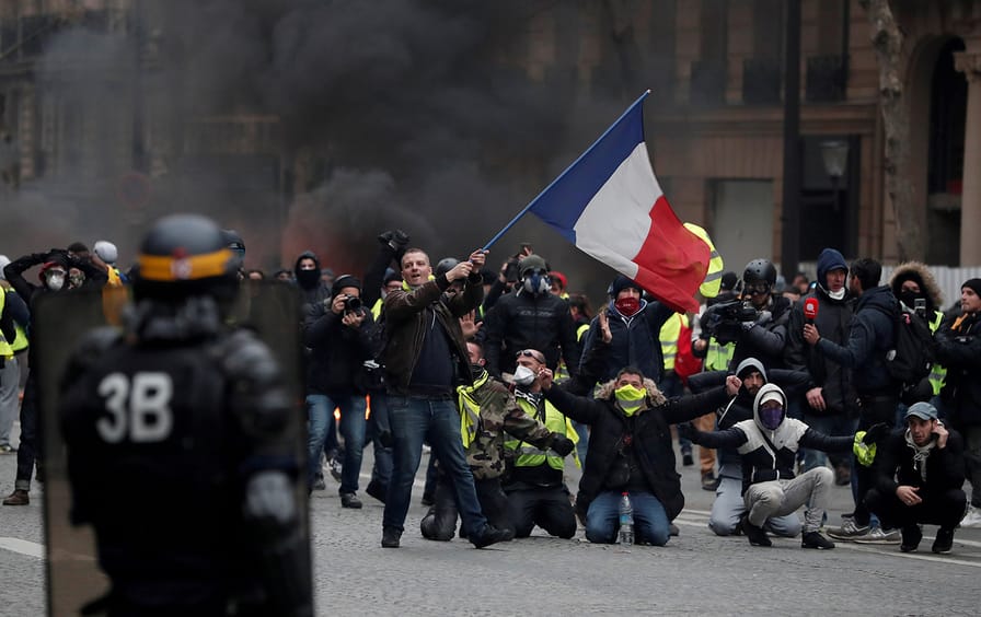 A protester waves a French flag during clashes with police at a demonstration by the 