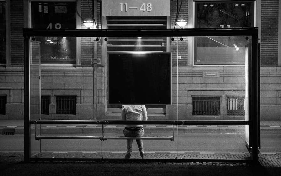 Woman at lonely bus stop.