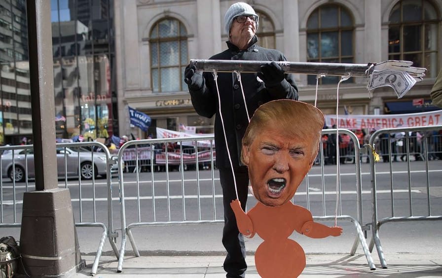 A Protester holds a Trump puppet