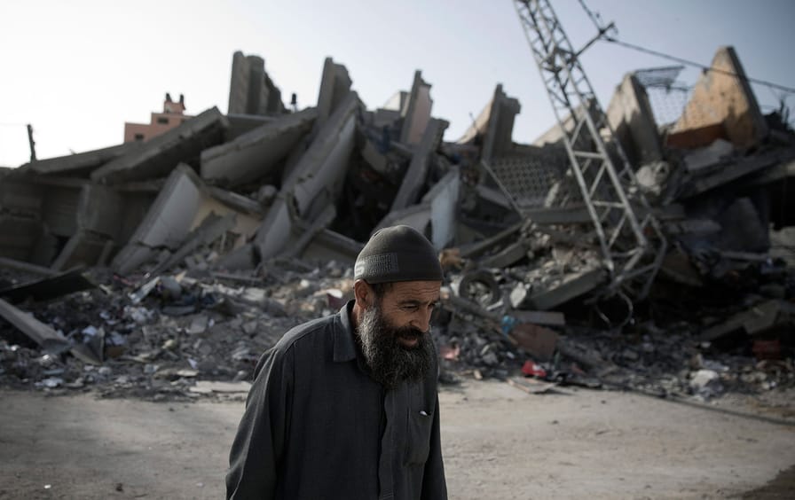 Eldery man walks by destroyed Gaza building