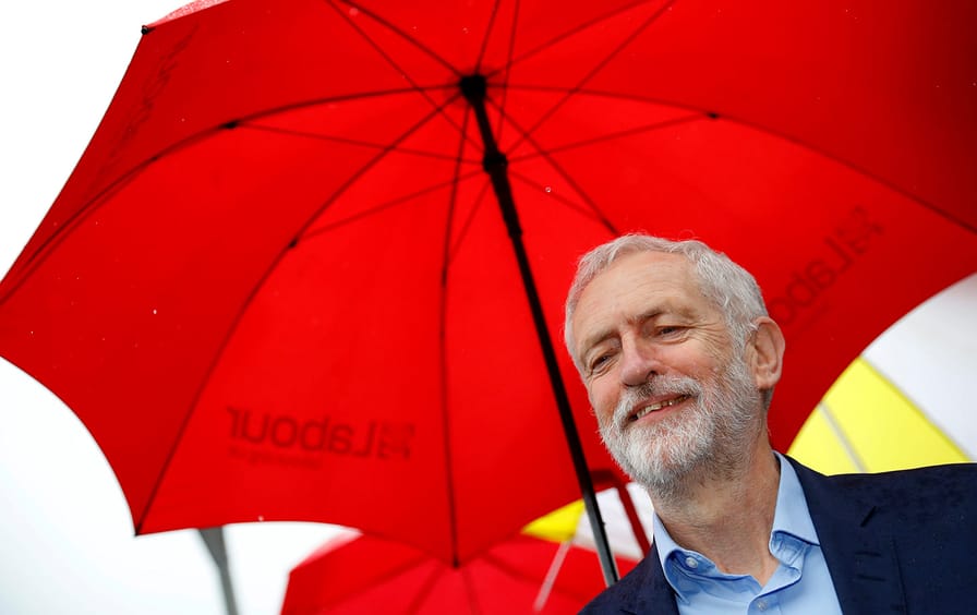 Jeremy Corbyn under a red umbrella.