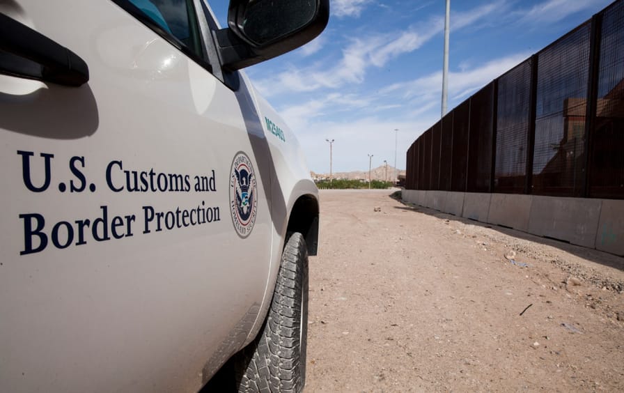A Customs and Border Patrol car near the border fence.