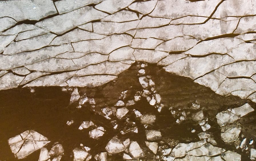 Aerial of broken ice in Helsinki bay melting into brown water.