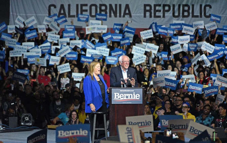 Jane and Bernie Sanders speaking to a large crowd in California.