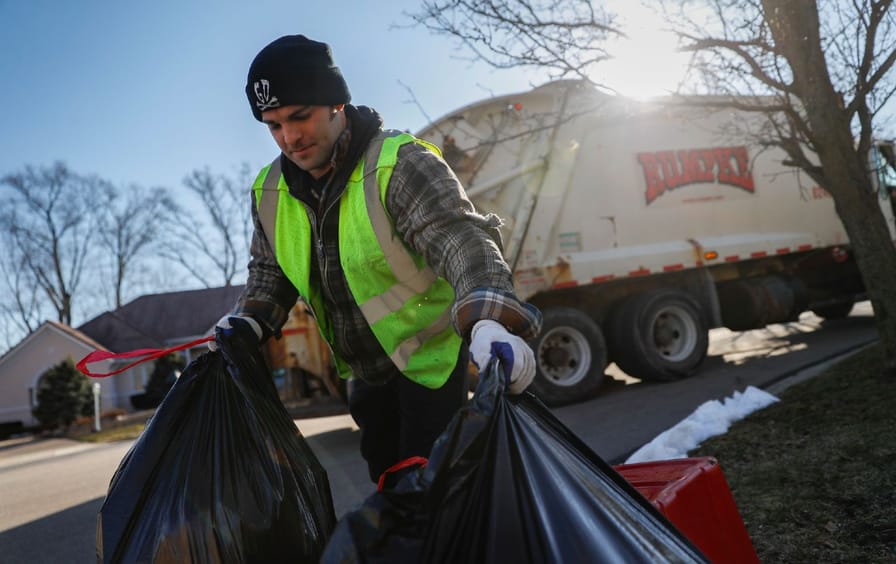 A sanitation worker hauls recycling bags in Beavercreek, Ohio.
