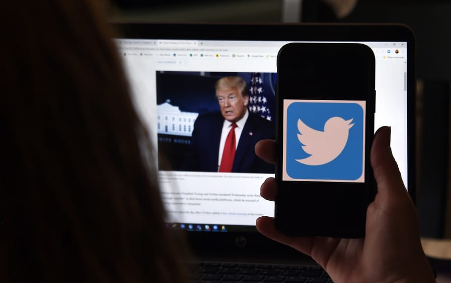 In this photo illustration, a Twitter logo is displayed on a mobile phone with President Trump's Twitter page shown in the background.