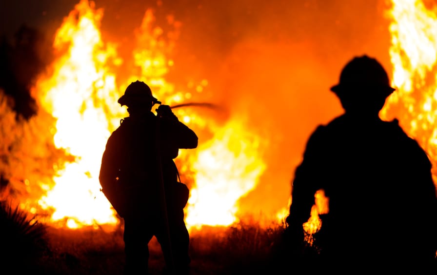 Firefighters stare into a fire.