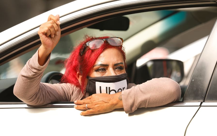 A woman with pink hair wearing a mask that says 