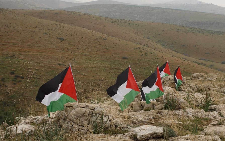 Five Palestinian flags planted in a row among rolling hills