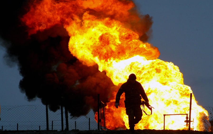 A soldier runs near a burning oil well i