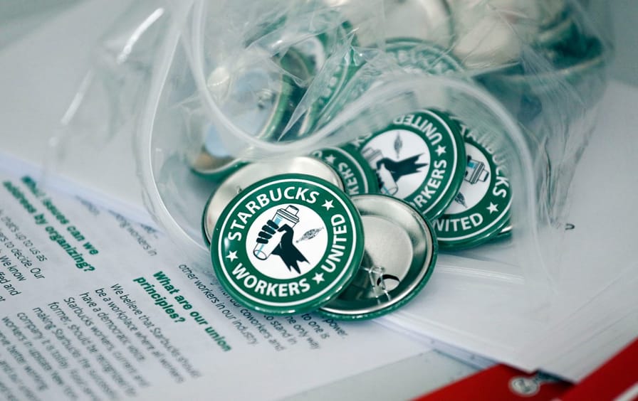 Starbucks union pins spill out of a bag onto union flyers