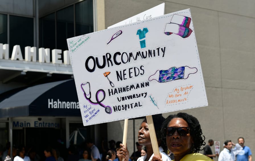 Women hold signs outside of Hahnemann University Hospital protesting its proposed closure.