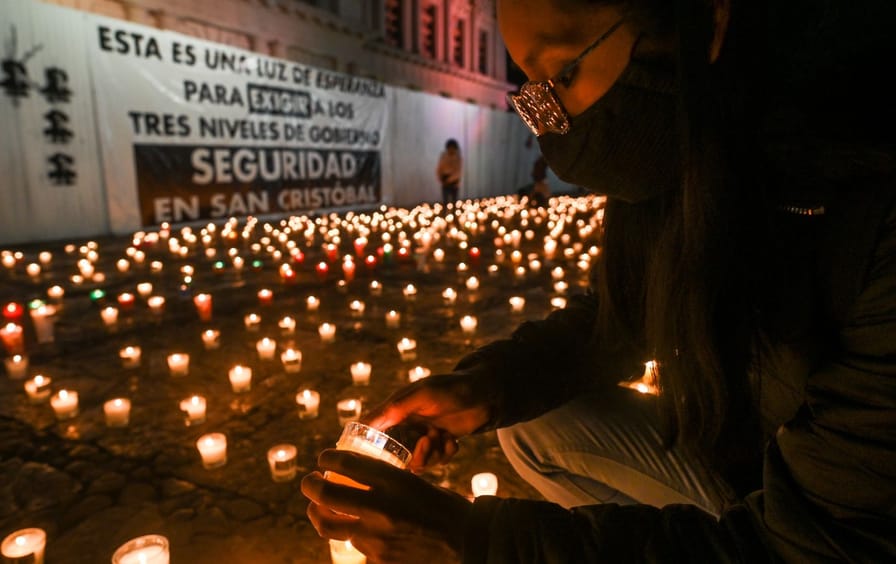 A woman lights a candle at a vigil.
