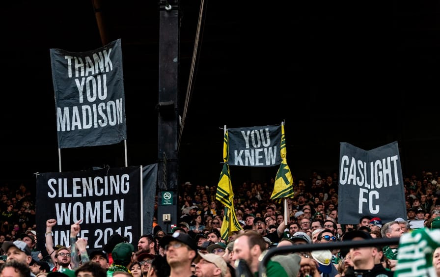 Portland soccer fans protest. Signs read. 
