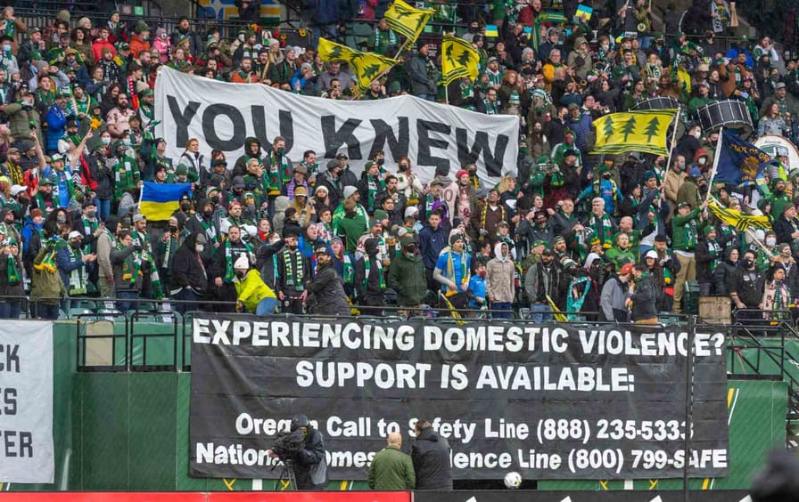 Fans dressed in green hold a banner that says 