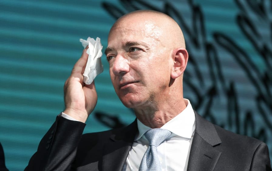 Jeff Bezos holds a handkerchief to his face.