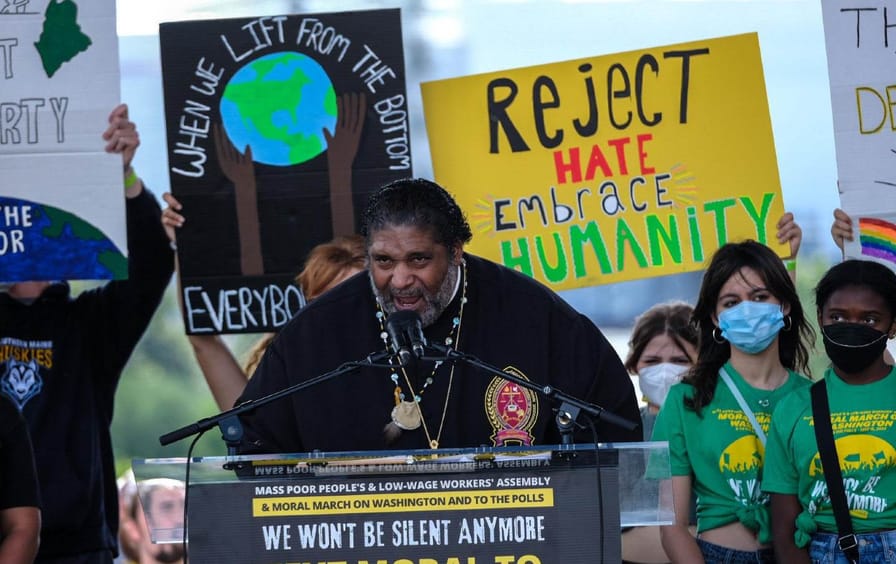 Reverend Barber speaking in front of signs