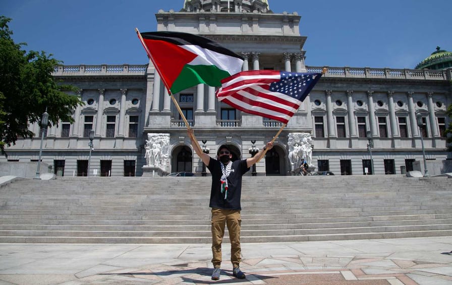 A demonstrator waves a Palestine flag and an American flag
