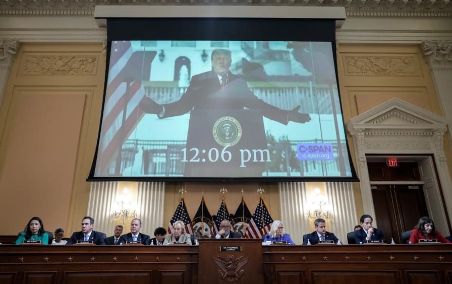 People sit below a screen with a screencap of Donald Trump from C-SPAN.