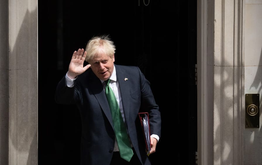 Outgoing British Prime Minister Boris John waves as he leaves 10 Downing Street to attend Prime Minister's Questions. He is holding a folder and wearing a suit with a green tie.