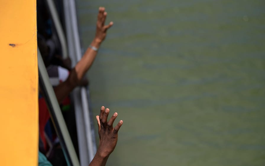 Haitian migrants reaching out of a boat