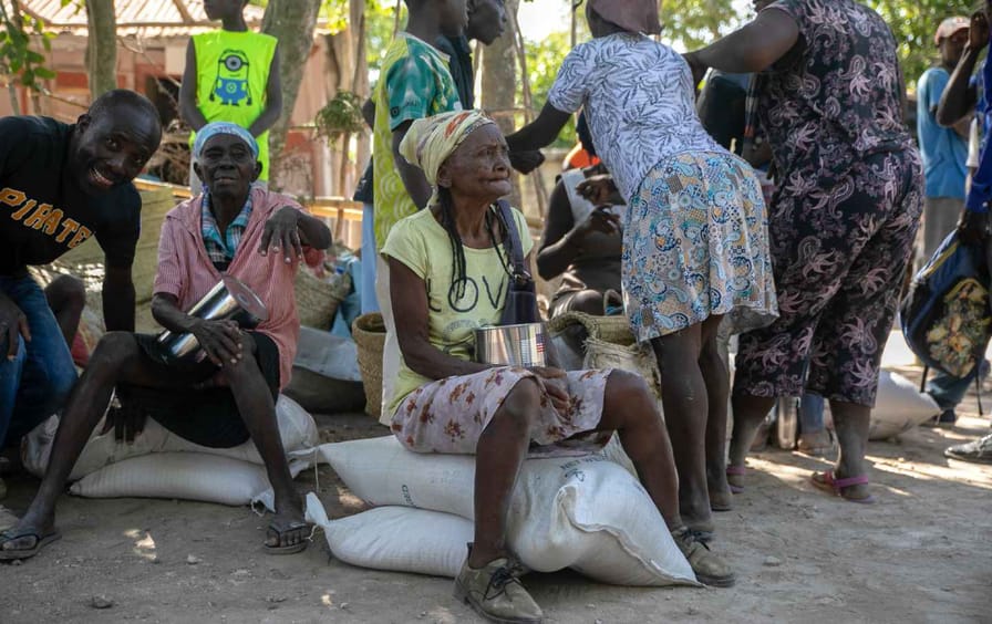 Residents of Jean-Rabel sit on sacks of food from the World Food Program.