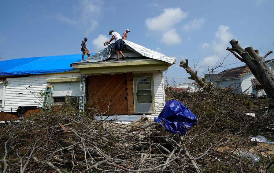Volunteers put a tarp on the roof of damaged home in the aftermath of Hurricane Ida, Thursday, Sept. 2, 2021, in Golden Meadow, La.