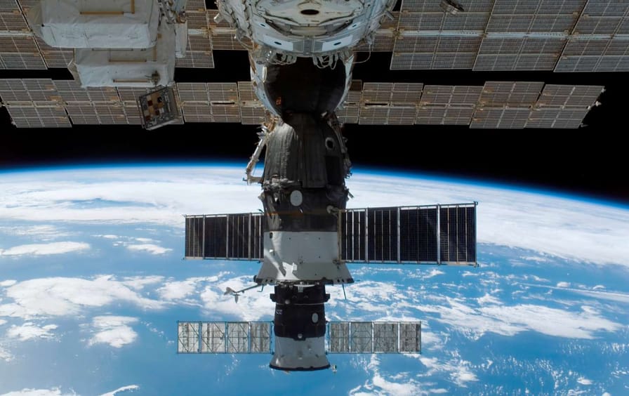 The docked Soyuz 14 and Progress 26 resupply vehicle at the International Space Station in 2007. The view of a blue and white Earth looms in the background.