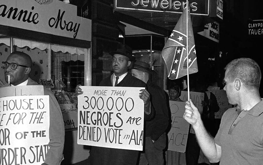 In this April 14, 1964 black-and-white file photo, a man holds a Confederate flag at right, as demonstrators, including one carrying a sign saying: 