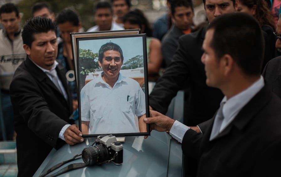 Framed photo of murdered journalist and a camera on top of a coffin.