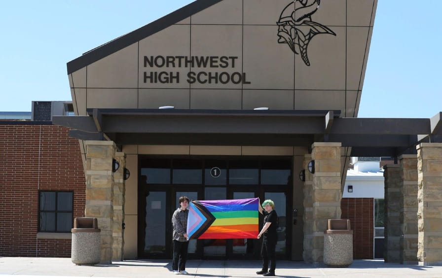 Graduates Marcus Pennell and Emma Smith hold up a Pride flag outside Northwest High School in Grand Island, Nebraska.