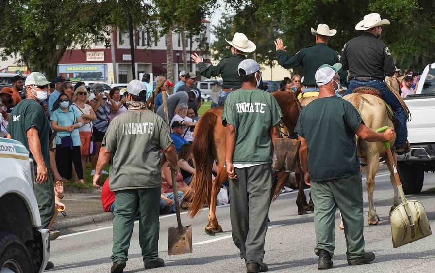 Jail inmates clean up after the police horses at the annual