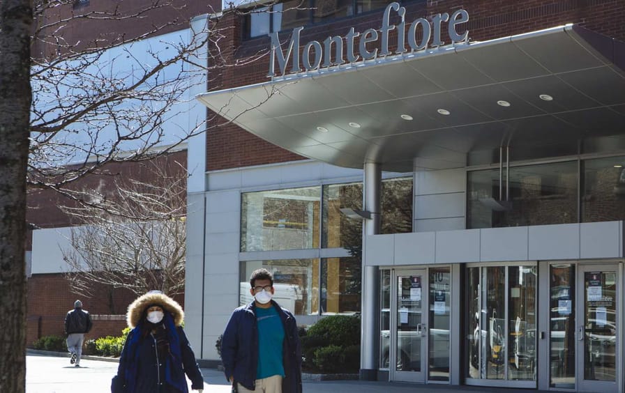 Pedestrians wearing protective masks pass in front of Montefiore Medical Center in the Bronx.